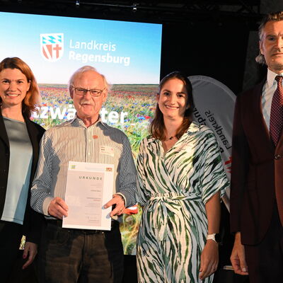 Bild vergr&ouml;&szlig;ern: Frau Landrätin Schweiger mit Bürgermeister und Vertreterin Landratsamt und zu Ehrendem auf der Bühne
