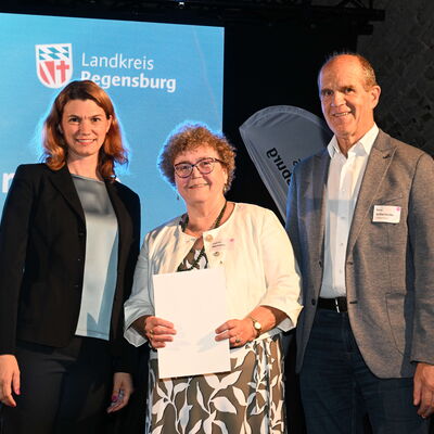 Bild vergr&ouml;&szlig;ern: Frau Landrätin Schweiger mit Bürgermeister Schleinkofer und zu Ehrenden auf der Bühne