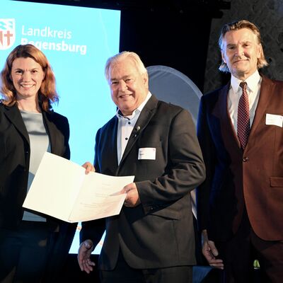 Bild vergr&ouml;&szlig;ern: Frau Landrätin Schweiger mit zu Ehrendem auf der Bühne am Ehrenamtsabend 2025