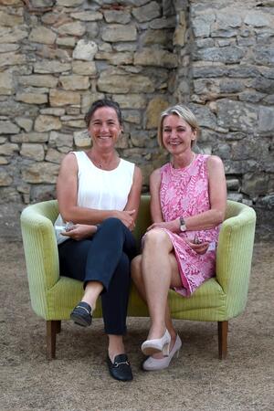 Bild vergr&ouml;&szlig;ern: Zwei Frauen sitzen auf einem gelben Sofa.