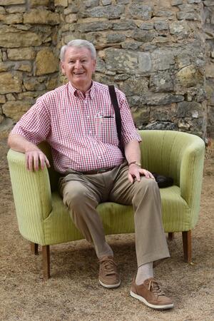 Bild vergr&ouml;&szlig;ern: Ein lächelnder Mann auf einem gelben Sofa.